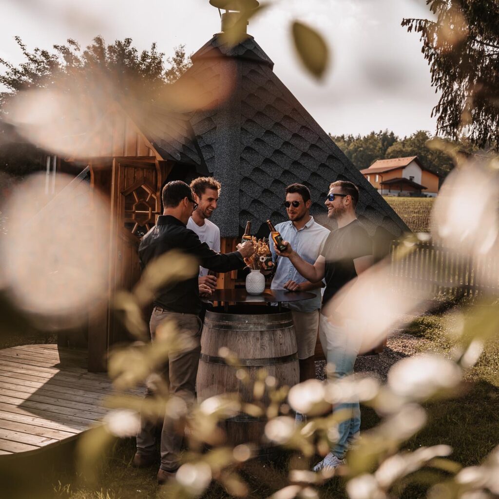 „Freunde stoßen bei sonnigem Wetter mit Bier an und genießen entspannte Momente im Freien – perfekte Inspiration für Geburtstagsfeier-Ideen in der Südsteiermark mit gemütlicher Atmosphäre und regionalem Flair.“